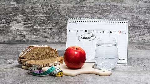 Diät-Mahlzeit vor grauem Hintergrund mit Kalender (Fastenzeit)