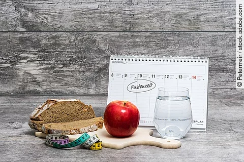 Diät-Mahlzeit vor grauem Hintergrund mit Kalender (Fastenzeit)