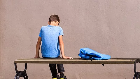 Trauriger Junge sitzt auf einer Bank