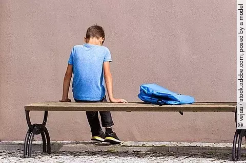 Trauriger Junge sitzt auf einer Bank
