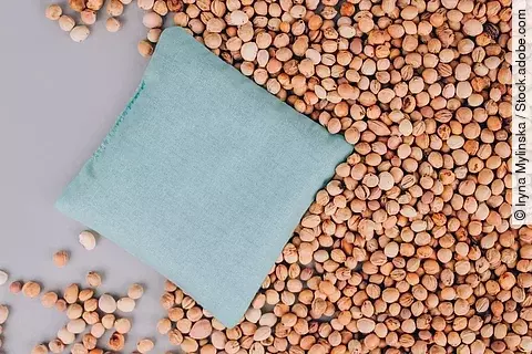 Ein Kirschkernkissen liegt inmitten von Kirschkernen.