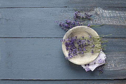 Lavendelblüten in einer Tonschale auf blauem Holz