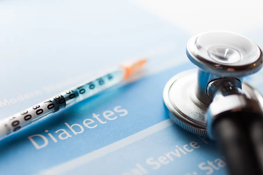 Spritze und Stethoskop liegen auf einem Schriftzug Diabetes
