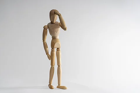 Stehende Holzgliederpuppe hält sich den Kopf, Kopfschmerz