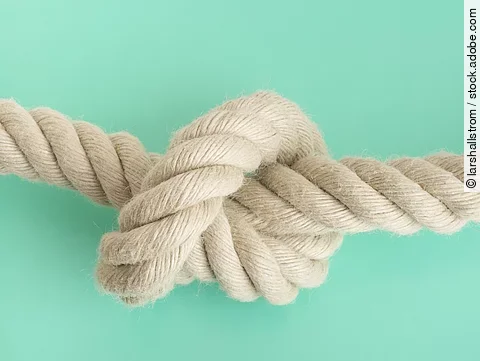 weißes Seil mit Knoten vor grünem Hintergrund