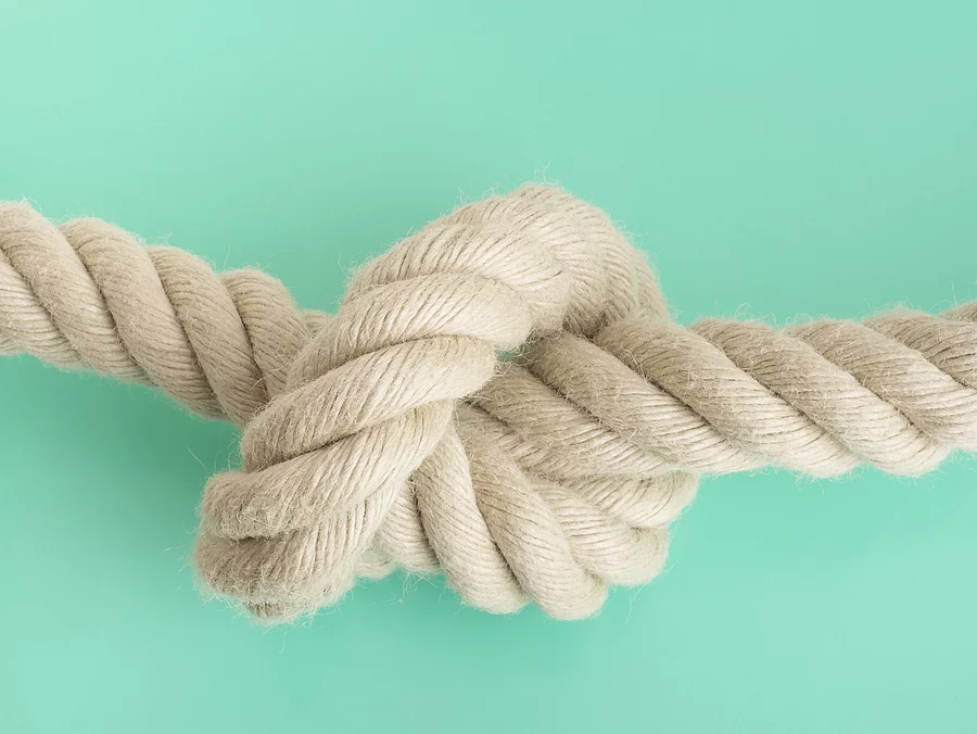 weißes Seil mit Knoten vor grünem Hintergrund