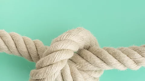 weißes Seil mit Knoten vor grünem Hintergrund