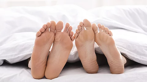 2 Fuß Paare schauen unter der Bettdecke hervor.