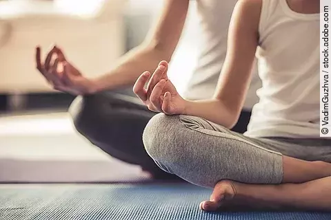 Zwei Frauen machen Yoga auf einer Matte.