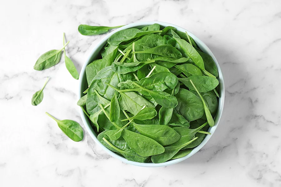 Fresh green healthy spinach on marble table, flat lay Frische Spinatblätter in einer Schüssel