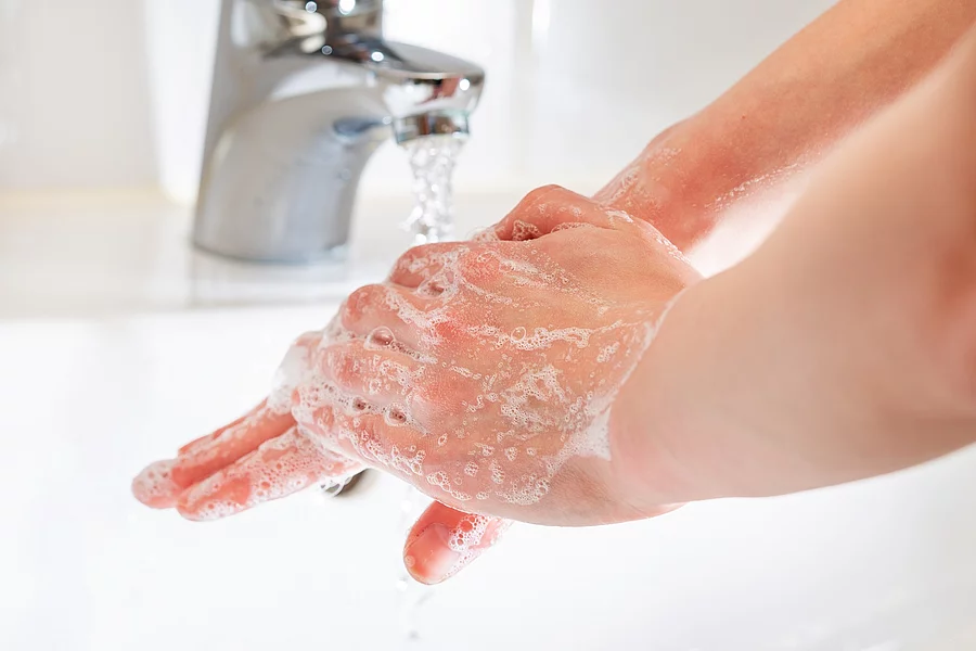 Händewaschen: eingeseifte Hände unter dem Wasserhahn
