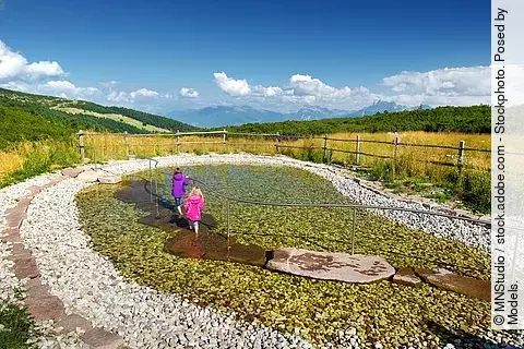2 Kinder beim Wassertreten in Berglandschaft