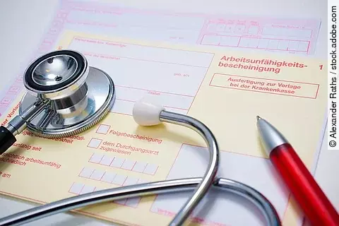 Arbeitsunfähigkeitsbescheinigung, auf der ein Stethoskop und ein Kugelschreiber liegen.