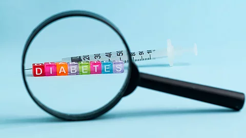 Lupe, dahinter bunte Würfel mit der Aufschrift Diabetes und eine Insulinspritze