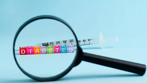 Diabetes: Lupe dahinter Insulinspritze und bunte Holzklötze mit der Aufschrift Diabetes