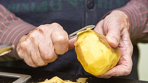 Seniorinnenhände schälen Kartoffeln