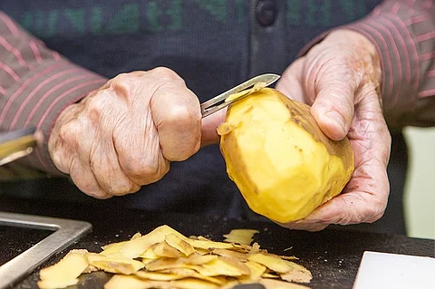 Seniorinnenhände schälen Kartoffeln