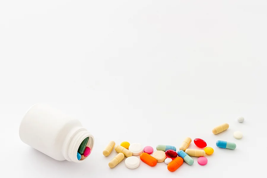 weißes Pillenfläschchen mit bunten Vitaminpillen