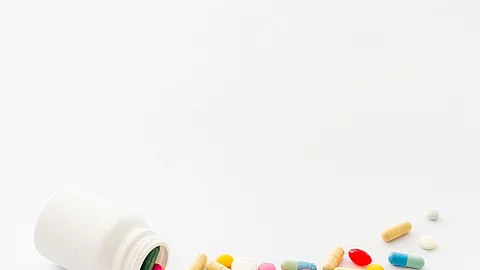 Weiße Pillendose und bunte Pillen und Kapseln weißes Pillenfläschchen mit bunten Vitaminpillen