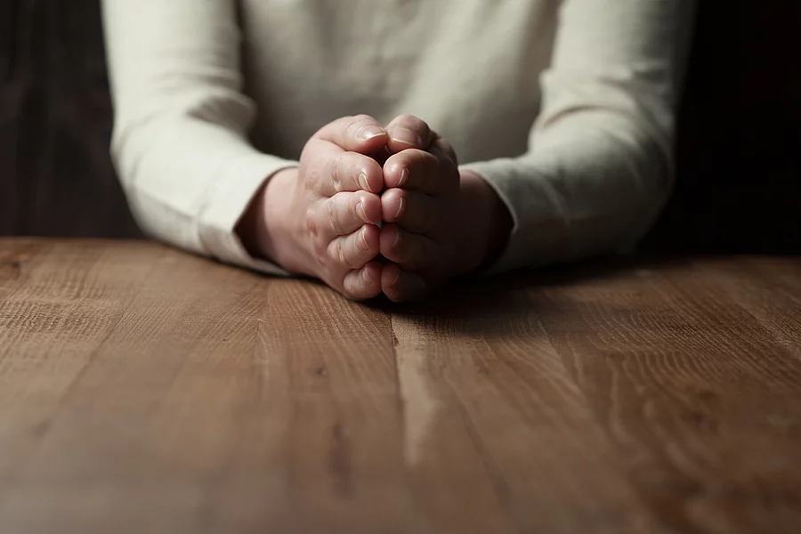 Betende Frau an einem Holztisch Betende Frau an einem Holztisch