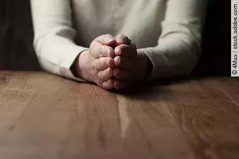 Betende Frau an einem Holztisch Betende Frau an einem Holztisch
