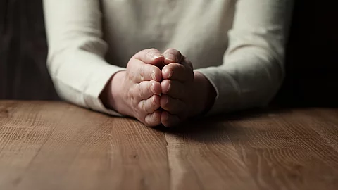 Betende Frau an einem Holztisch