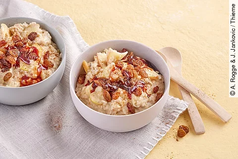 2 Müslischalen mit Haferporridge, Rosinen, Datteln auf einem Stofftuch