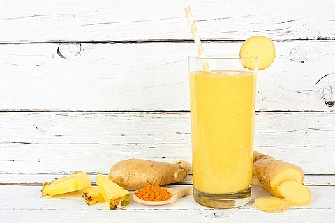Ananas Smoothie vor weißem Hintergrund in Holz Optik. 