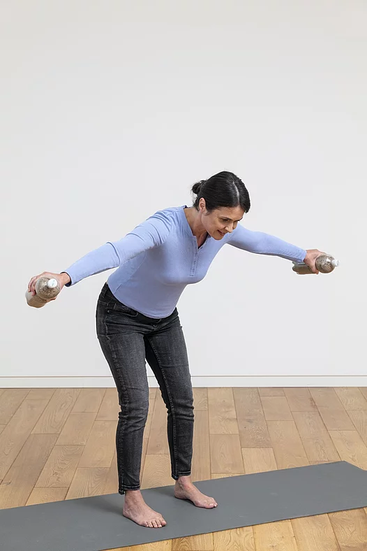Frau mach Übungen mit Wasserflaschen auf Yogamatte