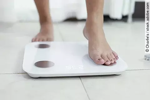 Füße einer Frau, die sich auf eine Waage stellt