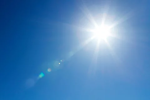 Sonne scheint vor blauem Himmel