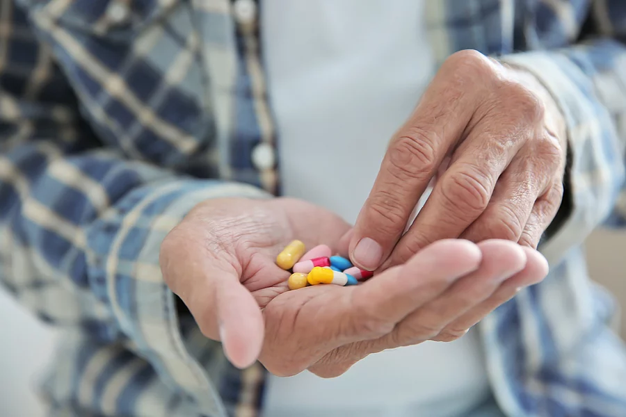 Senior hat Tabletten auf seiner Hand.