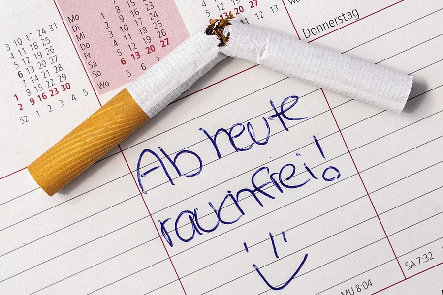 Kalender auf dem "ab heute rauchfrei" steht und eine durchgebrochene Zigarette liegt.