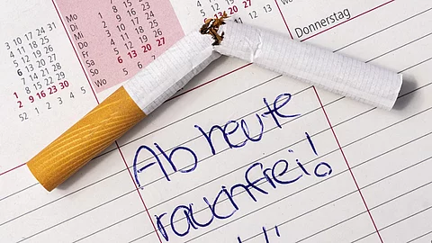 Kalender auf dem "ab heute rauchfrei" steht und eine durchgebrochene Zigarette liegt.