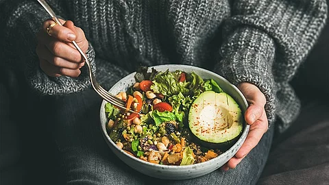 Healthy vegetarian dinner. Woman in jeans and warm sweater holding bowl with fresh salad, avocado, grains, beans, roasted vegetables, close-up. Superfood, clean eating, vegan, dieting food concept gesundes vegetarisches Essen, Frau in Jeans