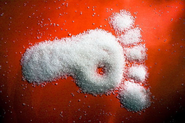 Fußabdruck aus Zucker auf rotem Hintergrund.