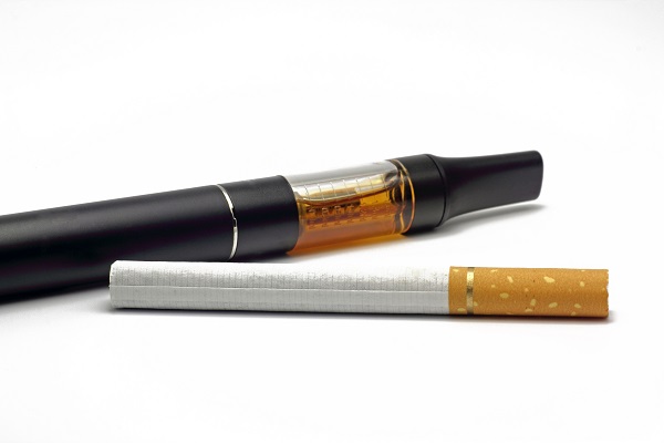 Herkömmliche Zigarette im Vordergrund, E-Zigarette im Hintergrund.