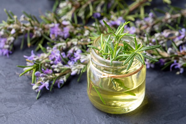 Rosmarin Öl Gefäß dekoriert mit Pflanze und Blüte.