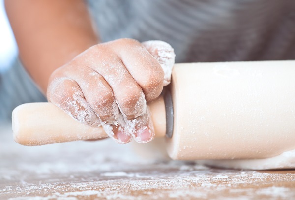 Kinderhände beim Teig ausrollen