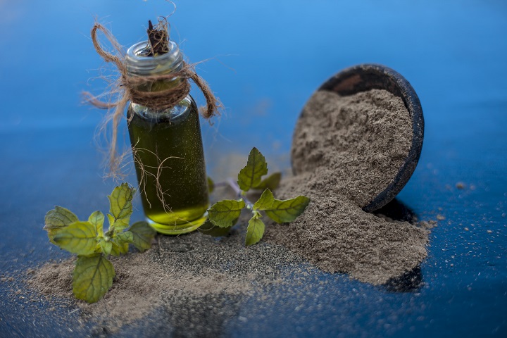 Ayurvedic herb brahmi or Waterhyssop with its essence in a small transparent glass bottle along with its powder on wooden surface. Ayurveda, Brahmi, Bacopa