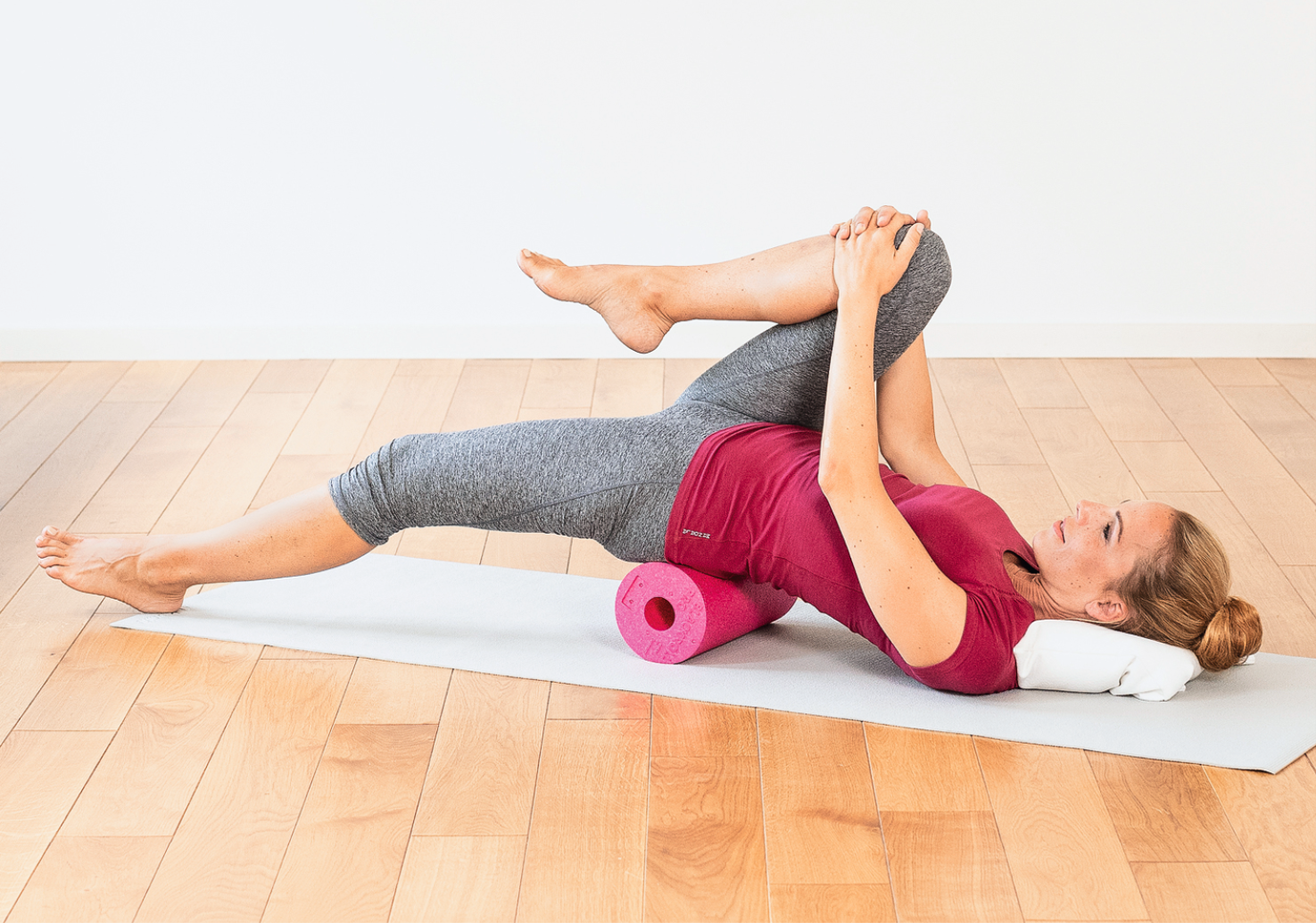 Frau in Rückenlage zieht rechtes gebeugtes Bein Richtung Schulter