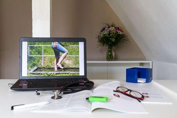 Symbolbild Integrative Medizin, Arztschreibtisch mit Stethoskop und Laptop mit Bild zu Kneipp-Wassertreten
