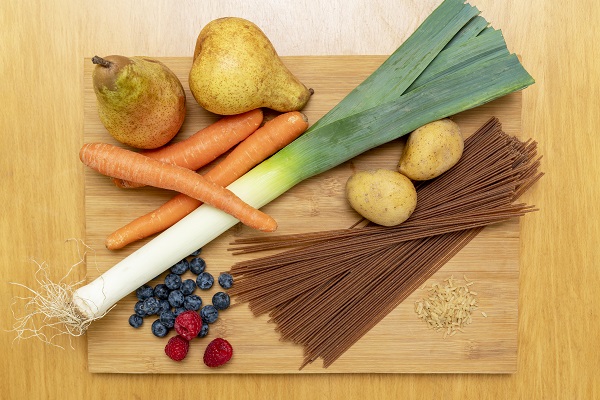 Birnen, Kartoffeln, Lauch, Vollkornspaghetti, Möhren, Beeren auf Holzbrett